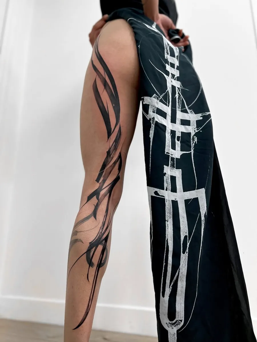 Tatouage d'Aether : calligraphie abstraite noire sur toute la jambe