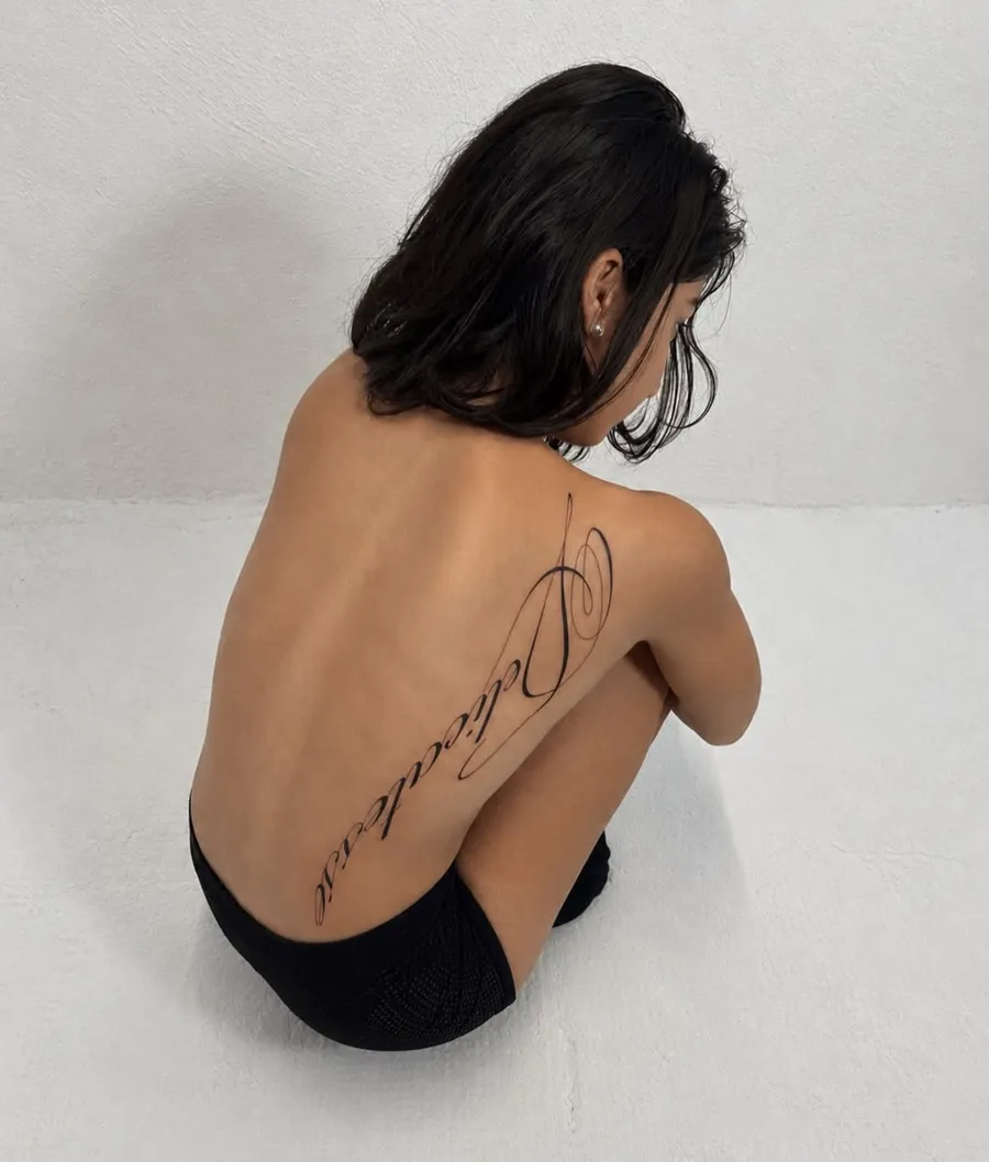 Tatouage de Saelen : lettrage calligraphique fin le long de la colonne
